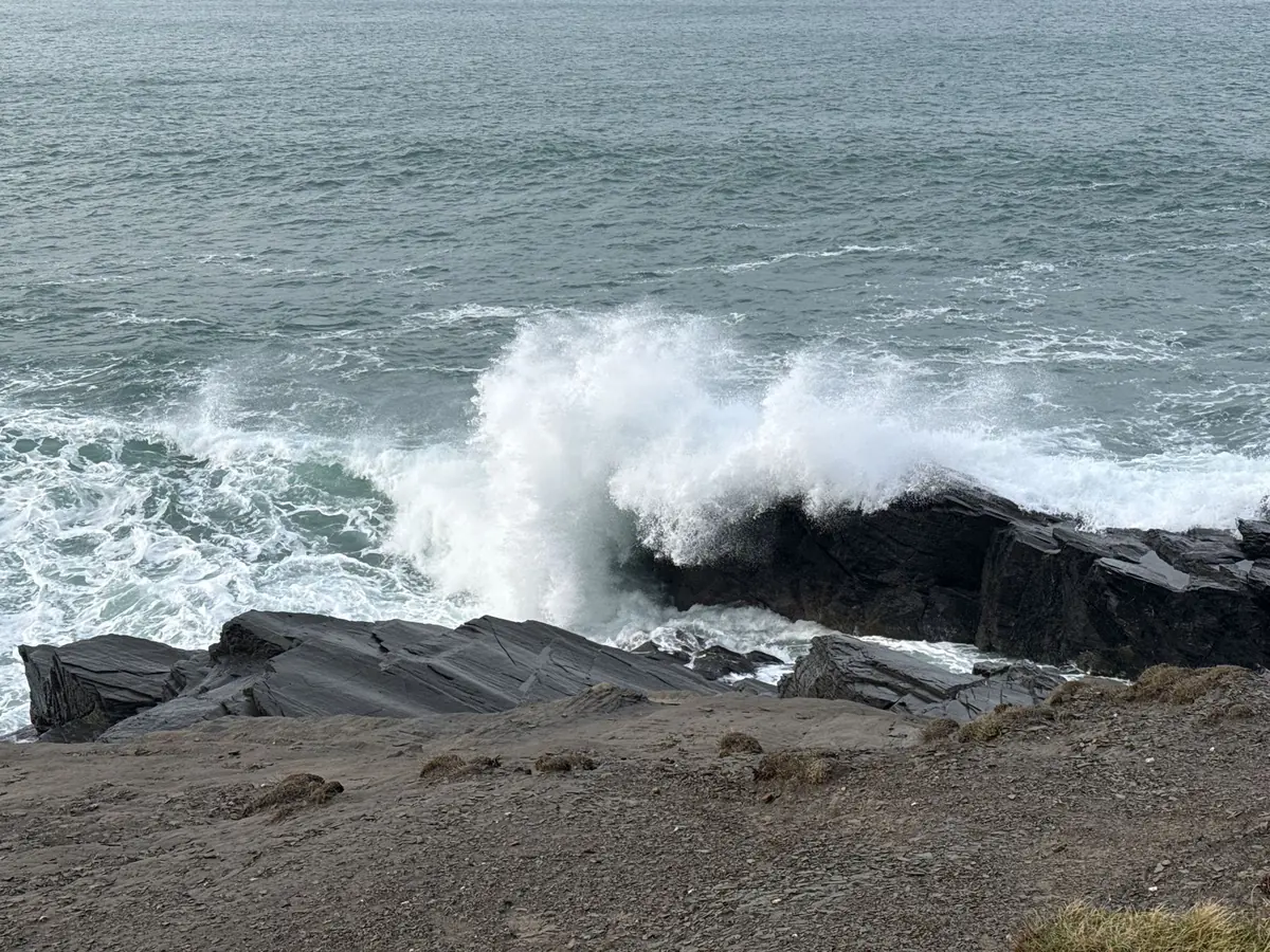 A wave exploding over a dark rock ledge