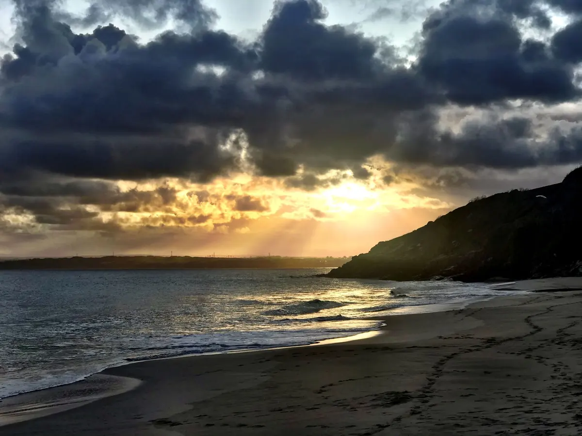 Sun rays breaking through storm cloud over a beach