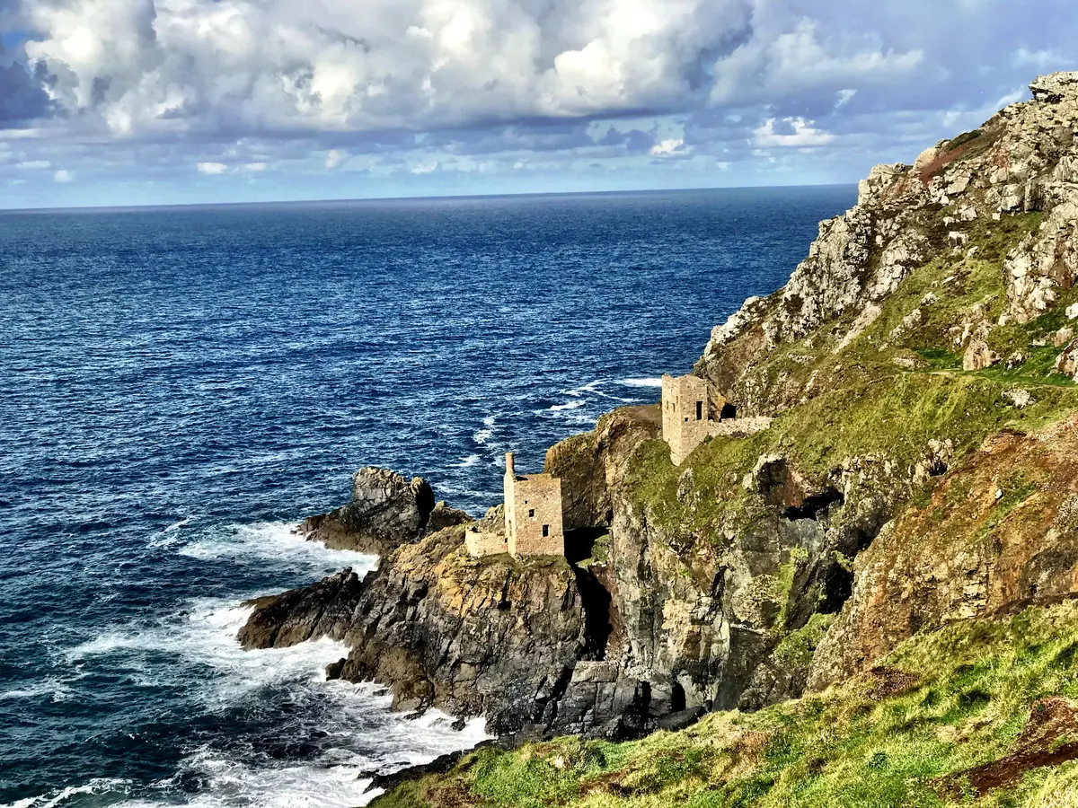 Two engine houses perched on rocks just above a deep blue sea