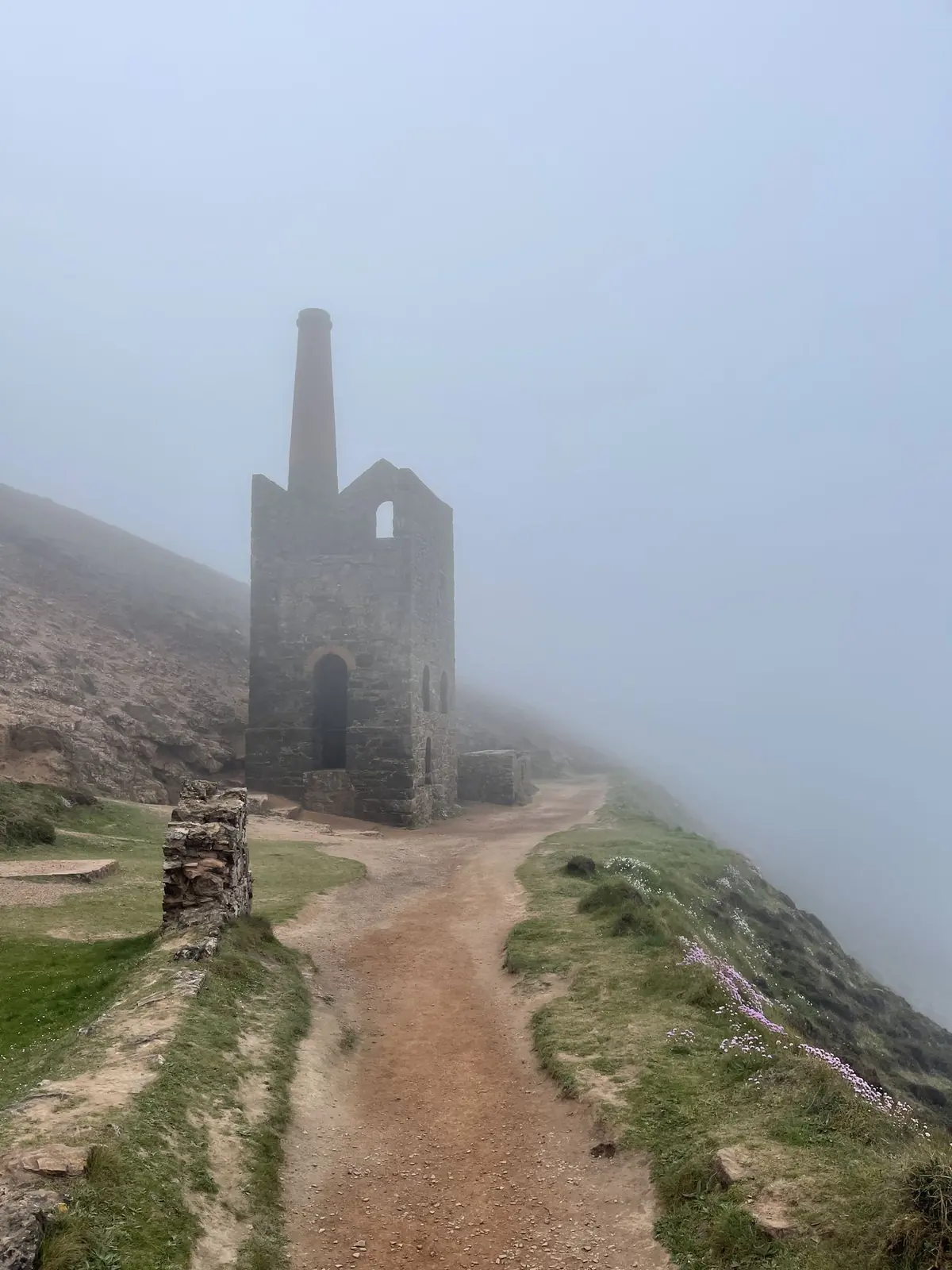 An engine house fading into thick fog at the end of a path