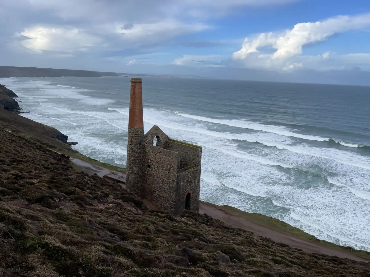 An engine house on a slope with lines of surf rolling in below