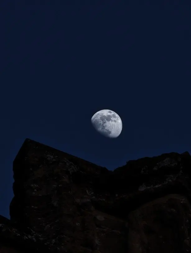 The Moon rising above the dark outline of a stone ruin