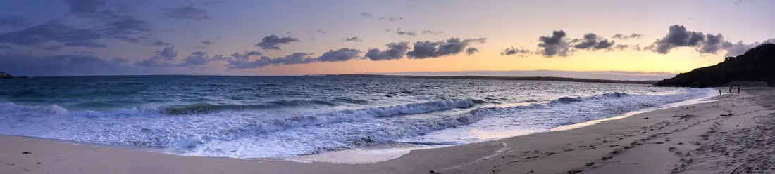 Panorama of surf running up a beach at dusk