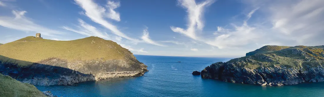 Panorama of two green headlands either side of a blue inlet